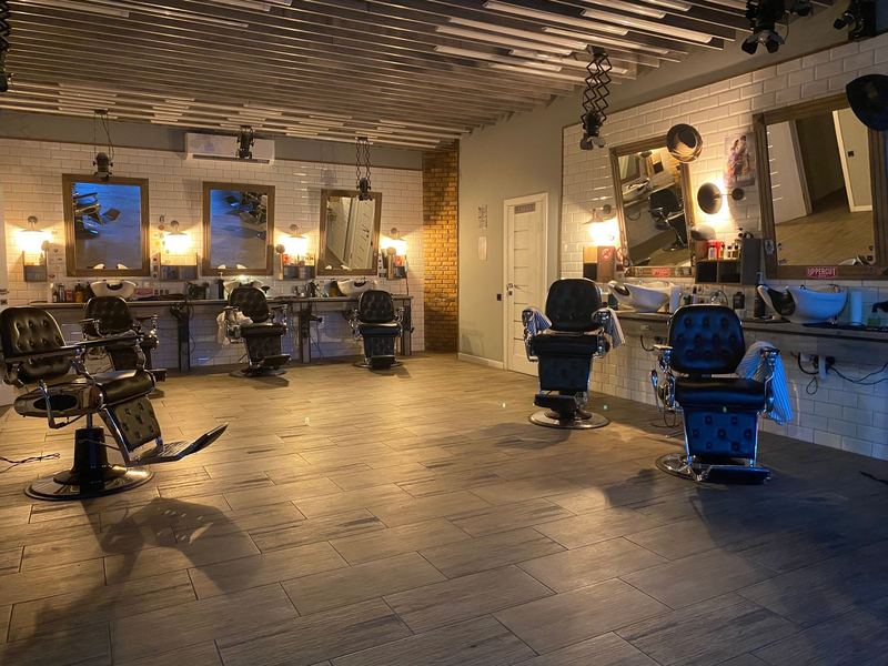 An empty barbershop: leather chairs, mirrors and warm wall lights.